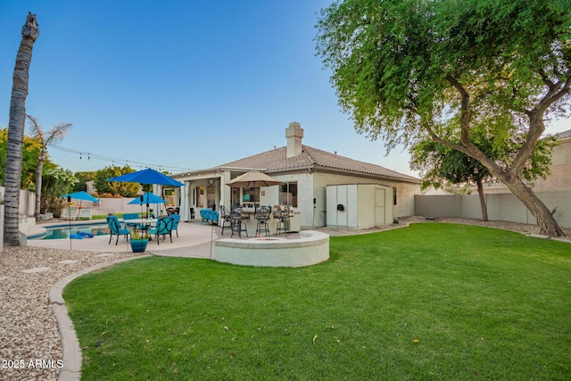 rear view of property with a patio, a fenced backyard, a yard, and a chimney