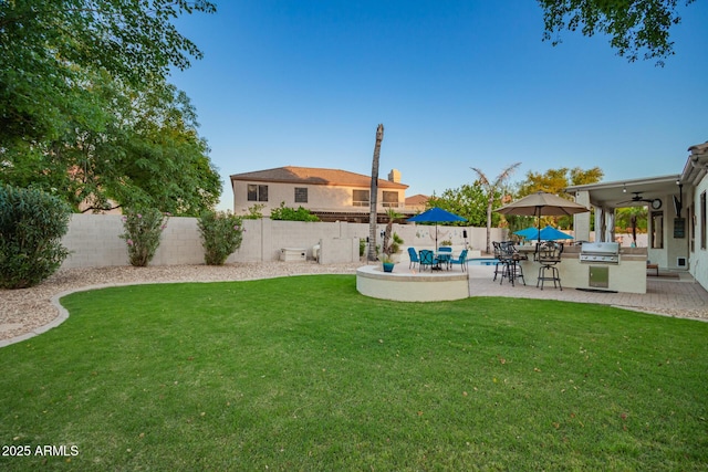 view of yard with a patio, an outdoor kitchen, ceiling fan, and a fenced backyard