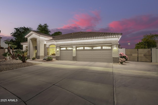 mediterranean / spanish-style house with a tiled roof, an attached garage, concrete driveway, and stucco siding