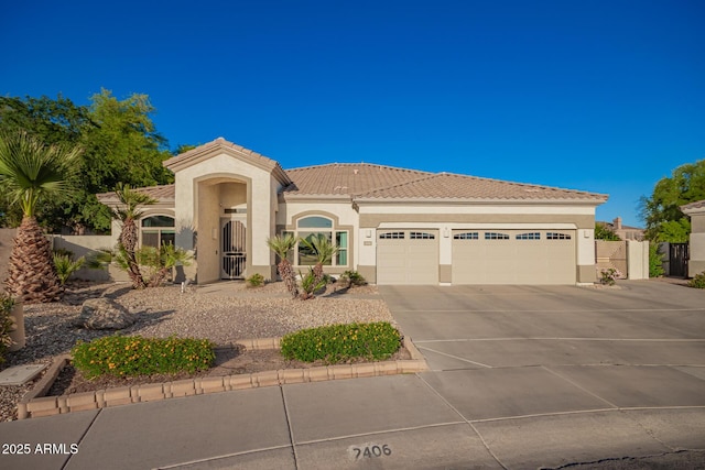 mediterranean / spanish home featuring an attached garage, stucco siding, driveway, and a tiled roof