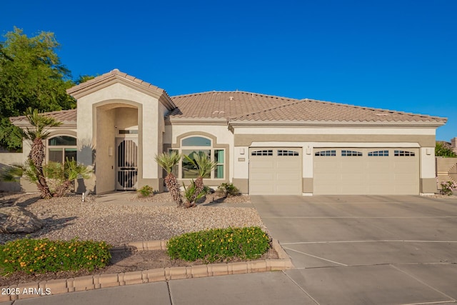 mediterranean / spanish house with a tiled roof, a garage, stucco siding, and driveway