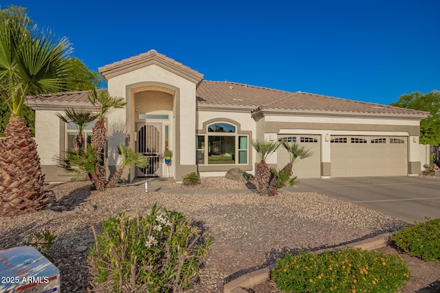 mediterranean / spanish-style house featuring concrete driveway, an attached garage, a tile roof, and stucco siding