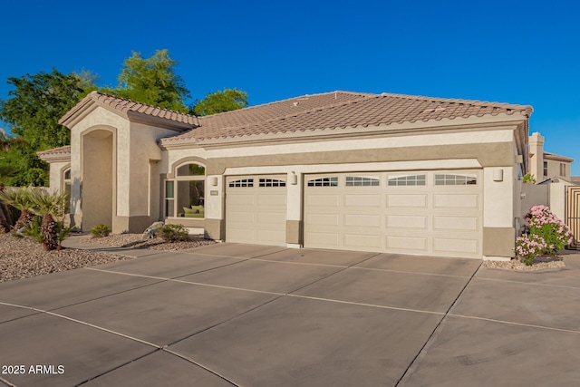 mediterranean / spanish-style home featuring a tiled roof, a garage, stucco siding, and driveway