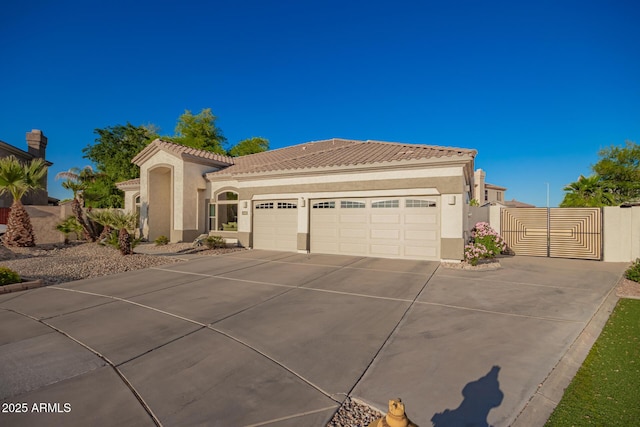 mediterranean / spanish-style home featuring a tiled roof, driveway, a gate, a garage, and stucco siding