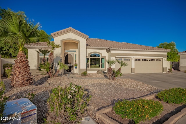 mediterranean / spanish house with concrete driveway, a tiled roof, a garage, and stucco siding