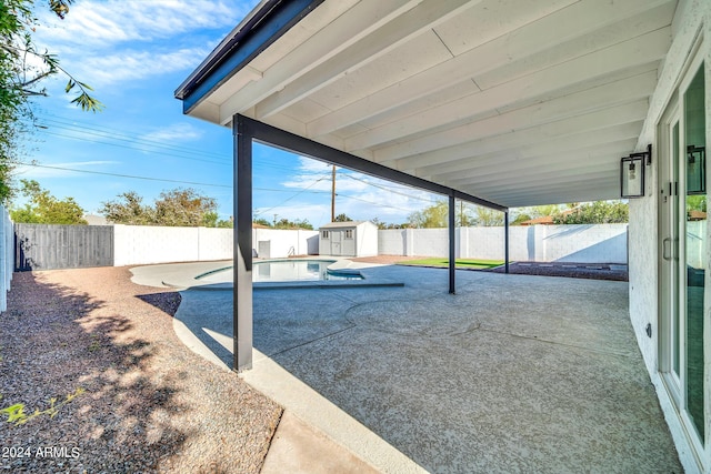 view of patio / terrace featuring a fenced in pool and a storage shed