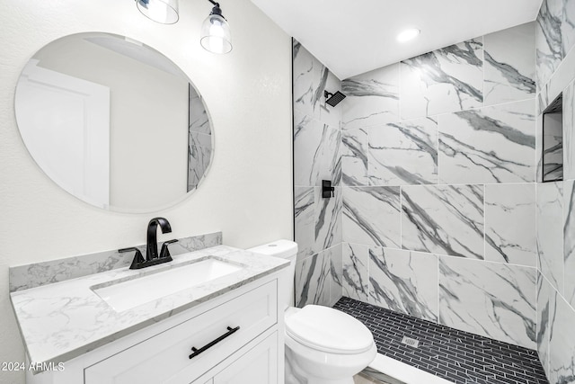 bathroom with tiled shower, vanity, and toilet