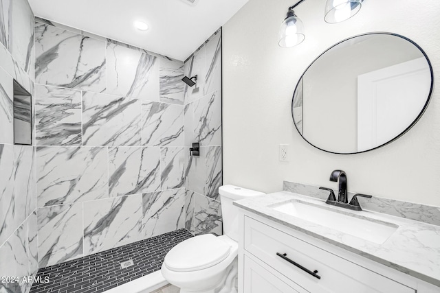 bathroom featuring tiled shower, vanity, and toilet