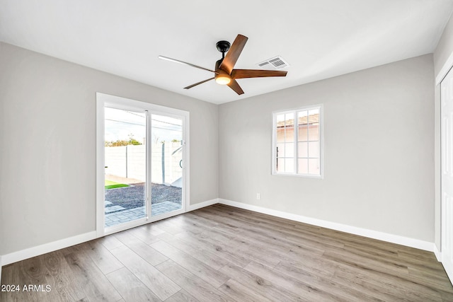 empty room featuring ceiling fan, light wood-type flooring, and a wealth of natural light