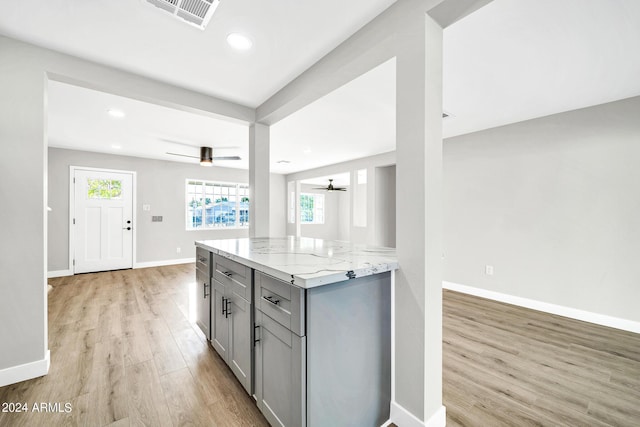 kitchen featuring gray cabinetry, light stone countertops, and light hardwood / wood-style floors