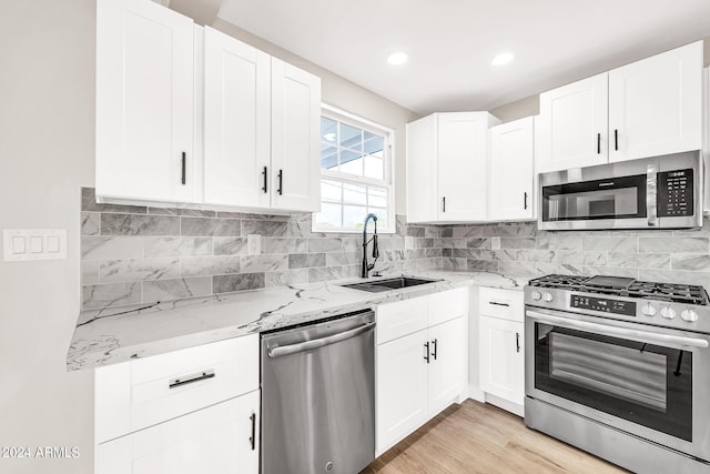 kitchen featuring white cabinetry, sink, stainless steel appliances, and light stone counters