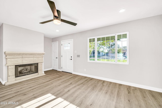 unfurnished living room with ceiling fan, a fireplace, and light hardwood / wood-style floors