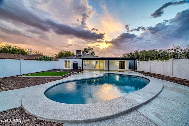 pool at dusk featuring a patio area