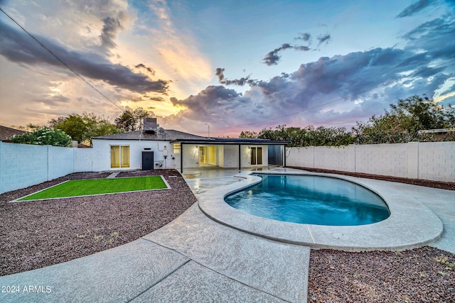 pool at dusk with a patio area and cooling unit