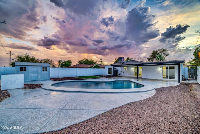 pool at dusk featuring a shed and a patio