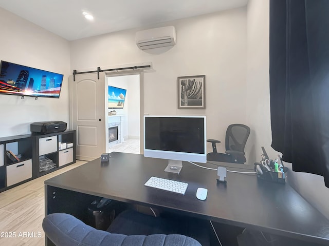 office area with a barn door, a wall unit AC, and light hardwood / wood-style flooring