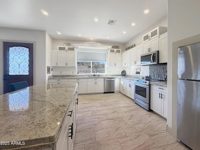 kitchen featuring stainless steel appliances, light stone countertops, and white cabinets