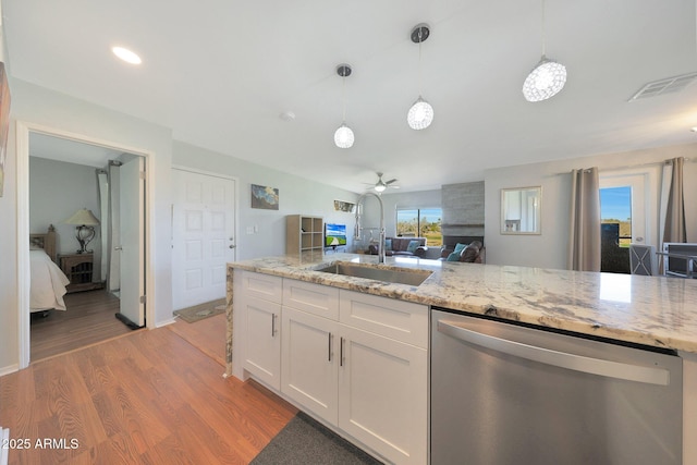 kitchen with white cabinets, dishwasher, light stone counters, hanging light fixtures, and light wood-type flooring