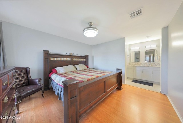 bedroom featuring visible vents, light wood-style flooring, and ensuite bath