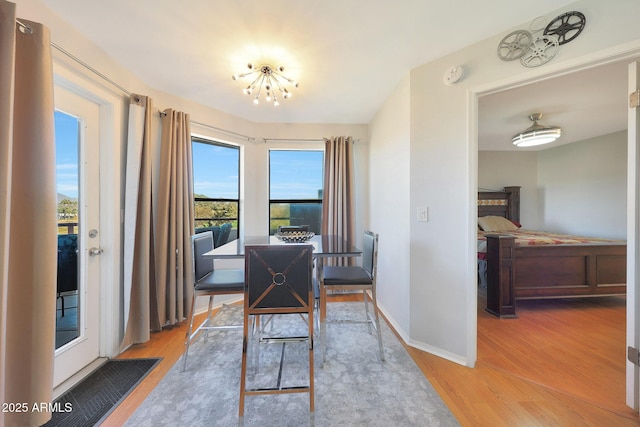 dining space with a notable chandelier, wood finished floors, and baseboards