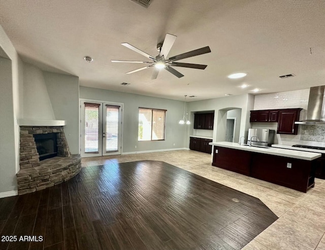 702 E Capricorn Way, Chandler, AZ 85249 - kitchen featuring wall chimney range hood, light countertops, open floor plan, ceiling fan, and a center island with sink