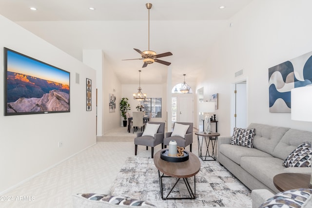 carpeted living room featuring ceiling fan with notable chandelier and high vaulted ceiling