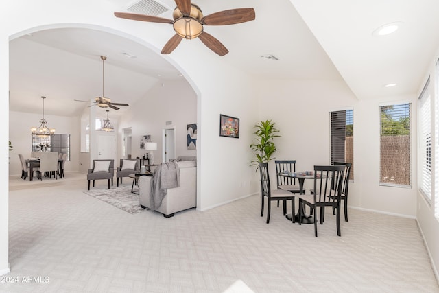 carpeted dining room with ceiling fan with notable chandelier and lofted ceiling