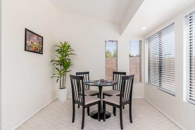 dining area with light colored carpet and vaulted ceiling