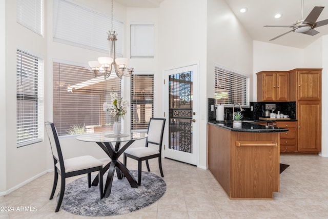 kitchen with high vaulted ceiling, ceiling fan with notable chandelier, pendant lighting, and sink