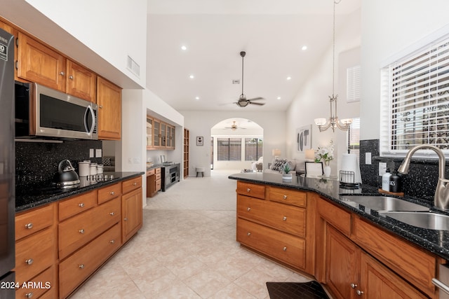 kitchen featuring dark stone counters, pendant lighting, sink, ceiling fan, and decorative backsplash