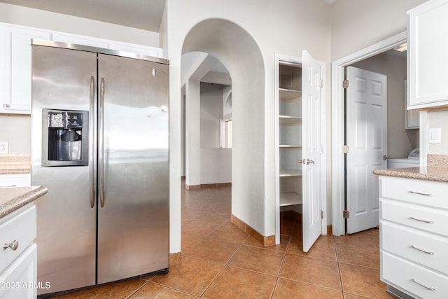 kitchen with baseboards, white cabinetry, stainless steel refrigerator with ice dispenser, and light tile patterned flooring