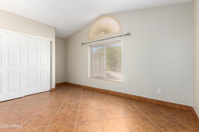 unfurnished bedroom featuring vaulted ceiling, baseboards, and tile patterned floors