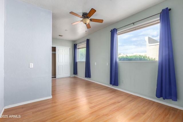 unfurnished room featuring ceiling fan, light wood-style flooring, and baseboards