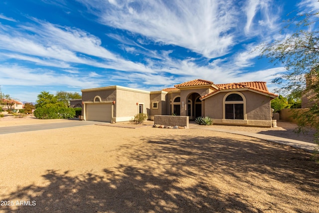 view of front of house featuring a garage, a tiled roof, concrete driveway, and stucco siding