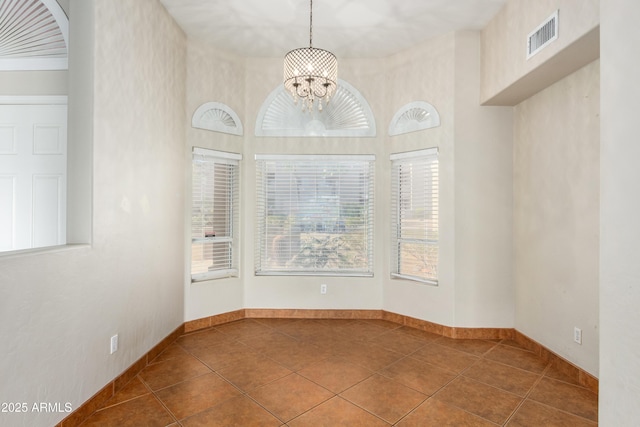 tiled spare room with baseboards, a high ceiling, visible vents, and a notable chandelier