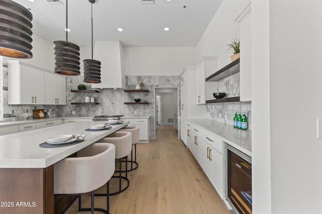 9611 E Clinton St, Scottsdale, AZ 85260 - kitchen with open shelves, beverage cooler, tasteful backsplash, a breakfast bar area, and white cabinetry