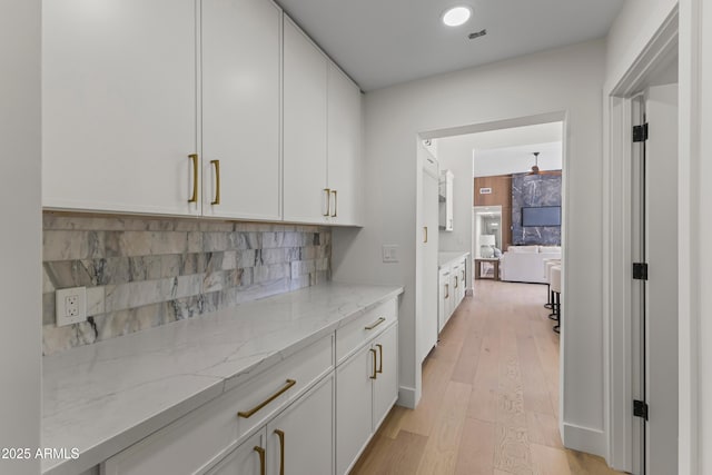 9611 E Clinton St, Scottsdale, AZ 85260 - kitchen featuring white cabinets, light stone counters, decorative backsplash, light wood-style flooring, and recessed lighting