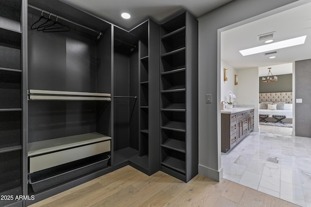9611 E Clinton St, Scottsdale, AZ 85260 - spacious closet featuring light wood-style flooring, a chandelier, and a sink