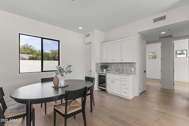 9611 E Clinton St, Scottsdale, AZ 85260 - dining space with beverage cooler, bar with sink, light wood-type flooring, and recessed lighting