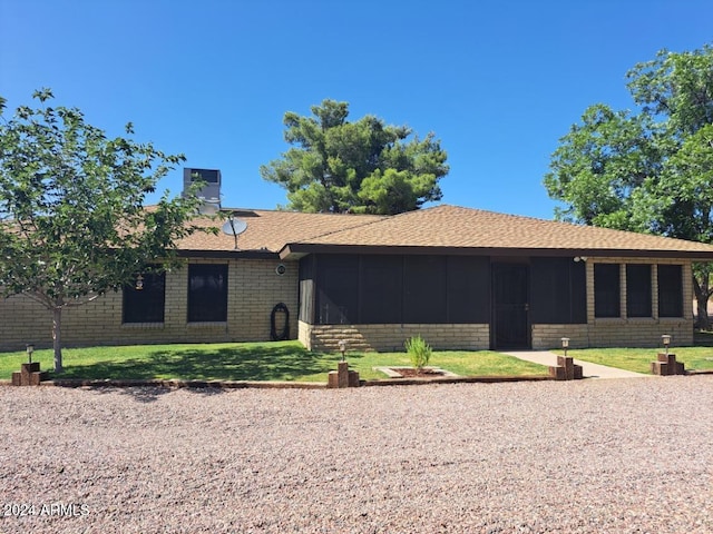 ranch-style house with a front yard and a sunroom