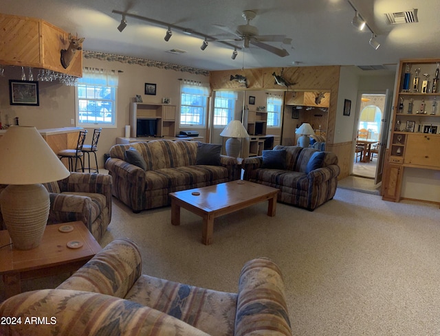 living room featuring wood walls, carpet floors, rail lighting, and ceiling fan