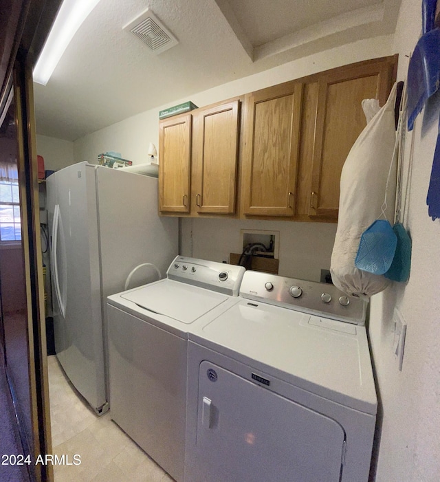 washroom featuring cabinets, a textured ceiling, and washing machine and clothes dryer