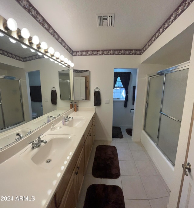 full bathroom featuring a textured ceiling, shower / bath combination with glass door, toilet, tile patterned floors, and vanity