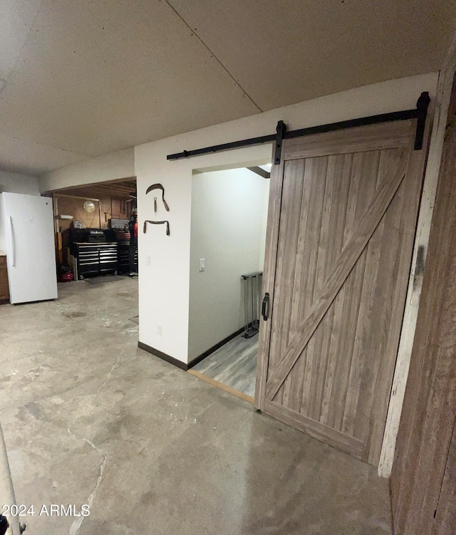 basement featuring a barn door, white fridge, and radiator