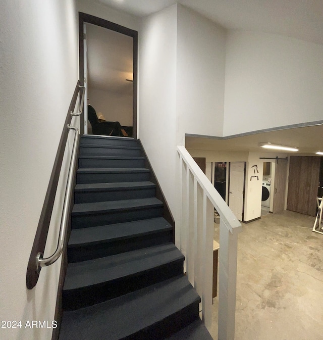 staircase featuring concrete floors and washer / clothes dryer