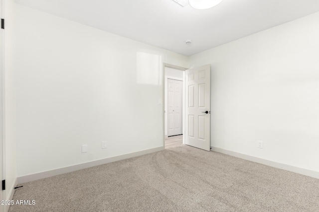 unfurnished room featuring light carpet and baseboards