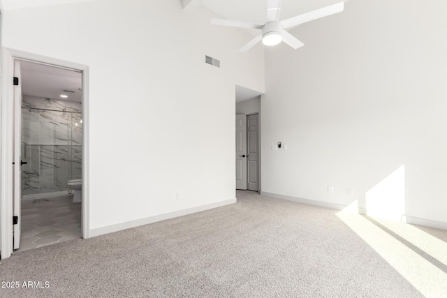 unfurnished bedroom with visible vents, a high ceiling, carpet flooring, connected bathroom, and baseboards