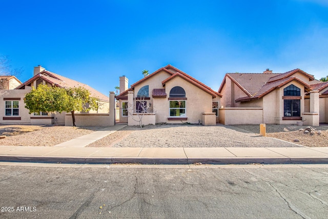 view of front of home featuring a tile roof, fence, a gate, and stucco siding