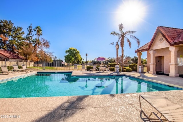 community pool with a patio area and fence