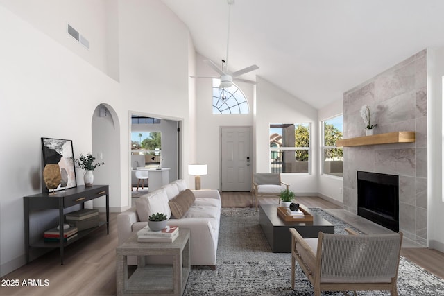 living room featuring ceiling fan, a fireplace, wood finished floors, and visible vents